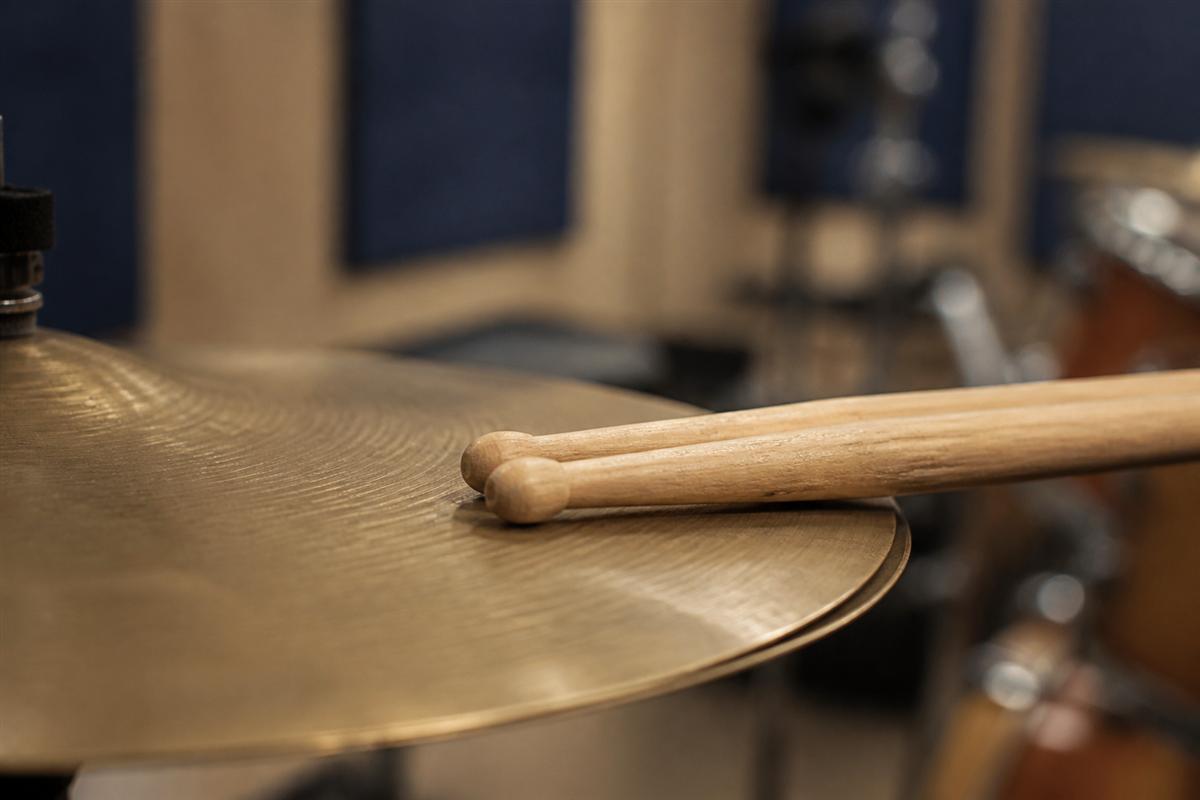 Maple drumsticks resting near a cymbal stand